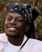 Jeune homme africain souriant qui porte un bandana noir et blanc et une chemise blanche.