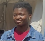 Jeune femme africaine au beau sourire et à la coiffure naturelle, qui porte un tee-shirt rouge sous une veste en jean