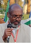 Homme africain à la barbe grisonnante et lunettes larges qui tient un micro